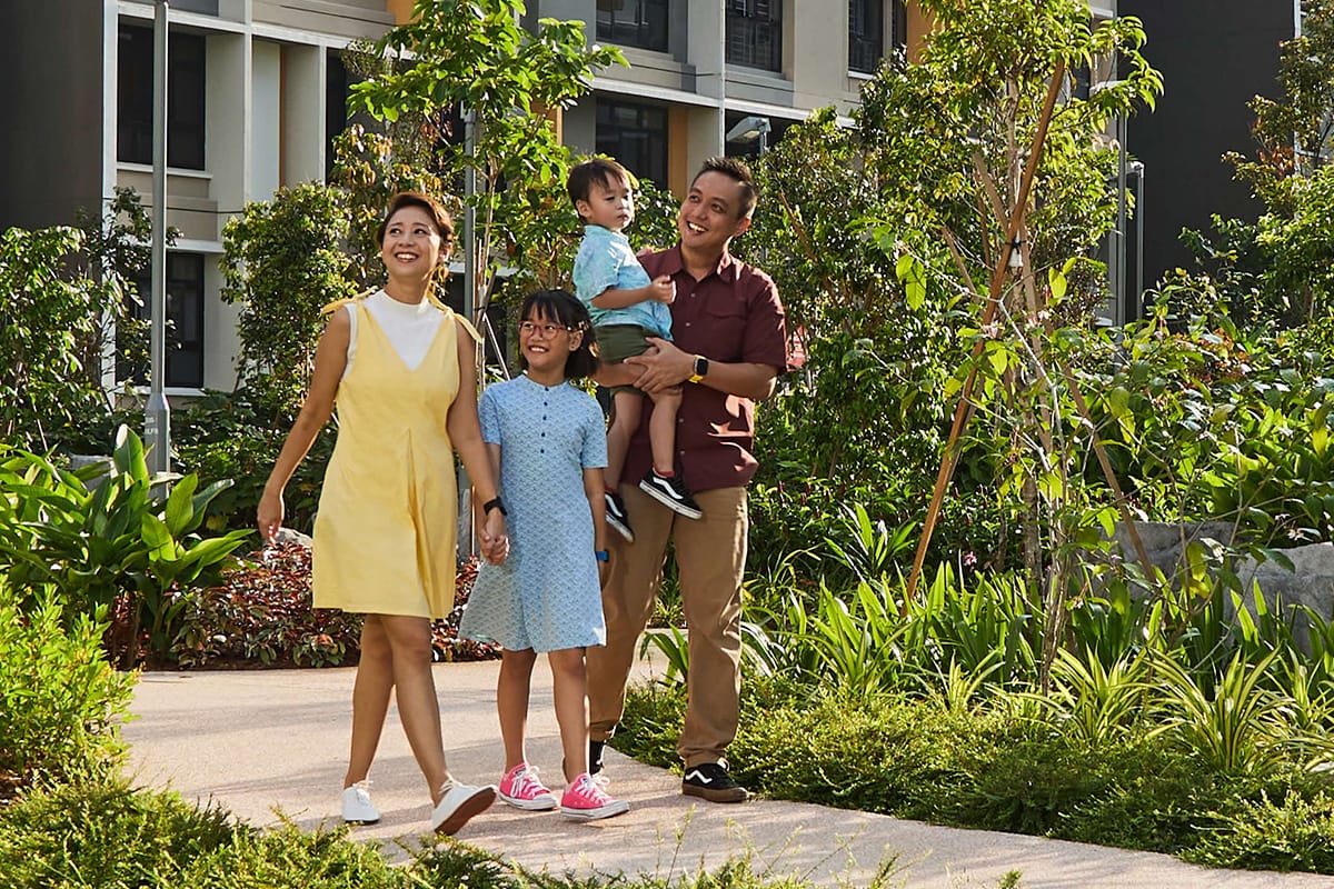 A family walking through a common area in an HDB estate, surrounded by lush greenery.